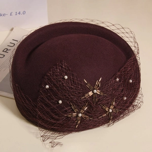 Close-up of dark red wool pillbox hat with mesh veil and pearl star details