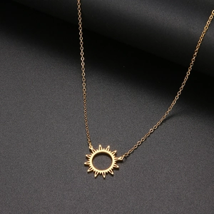Détail du pendentif soleil doré avec motif rayonné sur une fine chaîne élégante