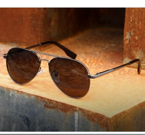 Classic pilot sunglasses with brown gradient lenses and metal frames on a vintage surface