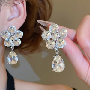 Macro view of sparkling crystal flower earrings with a large teardrop pendant on ear