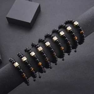 Detail of A-Z alphabet beads on black onyx and tiger eye stone bracelets displayed on a rack
