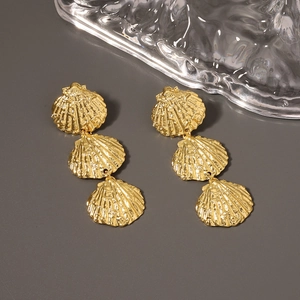 Detail shot of three-tier golden shell earrings with a metallic finish and ocean theme