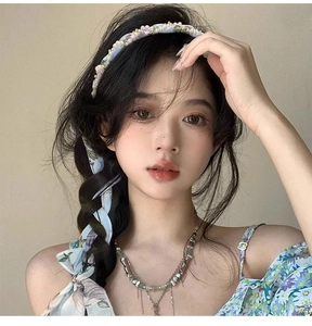 Floral hairband with blue flower patterns and elegant pearl bead details shown on a model