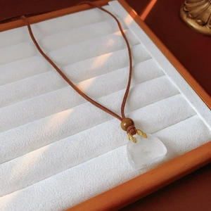 Close-up of retro necklace with wood beads and stone pendant on a white velvet display