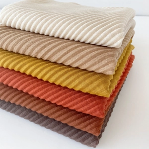 Detail of stacked 90cm pleated square scarves showing ribbed texture in earth tones