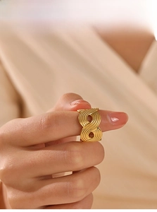 Macro detail of golden stainless steel ring featuring a textured infinity twist design
