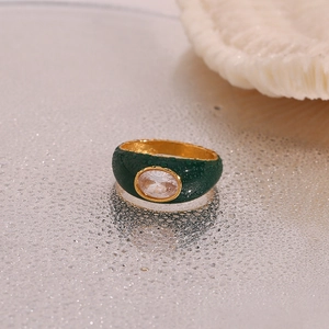 Detail of 18K gold stainless steel ring with oval zircon and green enamel with water drops