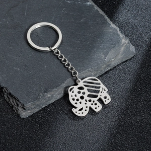Polished stainless steel elephant keychain with intricate hollow design on rock background