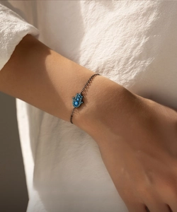 Detailed macro view of S925 silver Hamsa palm bracelet with blue evil eye on wrist