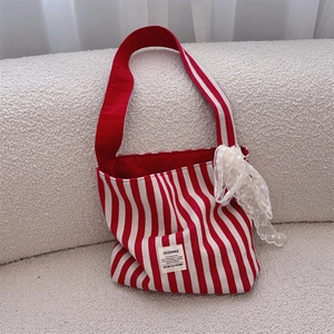 Detailed shot of red striped canvas bag featuring a delicate white lace bow accent