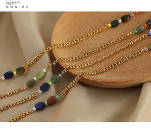 Detail of vintage gold plated steel chain with colorful geometric beads on silk