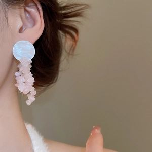 Close-up of pink stone tassel earrings with white circular accents on a female model
