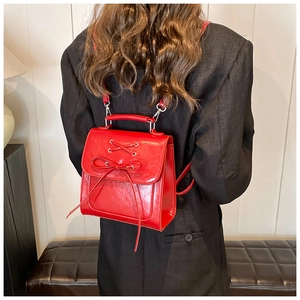 Detail of red PU leather backpack featuring lace-up bow design and metallic hardware