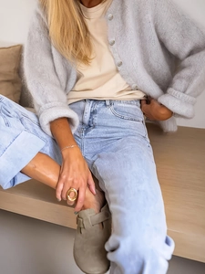 Detalle de cárdigan de punto gris claro con camiseta beige y vaqueros de lavado claro