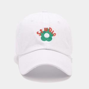 Close-up of STUDIO text and green flower embroidery on white cotton baseball cap