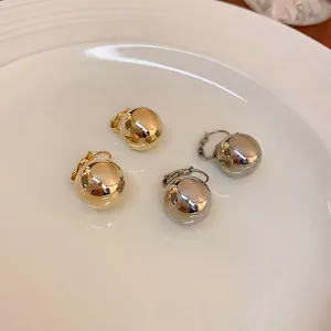 Boucles d'oreilles boules minimalistes dorées et argentées sur un plateau blanc
