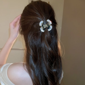 Dettaglio di un fermaglio per capelli a farfalla a doppio strato con zirconi e conchiglia