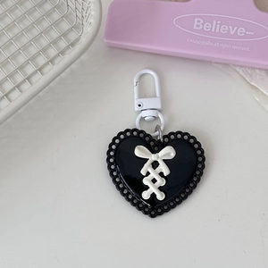 Detail of Y2K heart keychain featuring a black resin base and white ribbon bow tie design