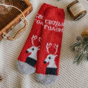 Detail of red Christmas coral fleece socks with reindeer pattern and festive text