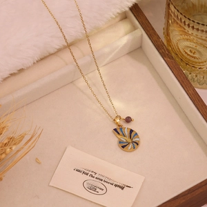 Detail of gold titanium necklace with blue enamel shell pendant in a jewelry box