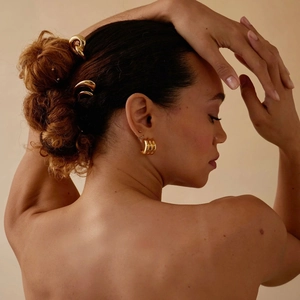 Macro detail of the smooth 18k gold-plated pretzel hair stick and matching earrings
