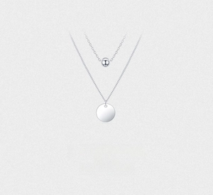 Detail of minimalist 925 silver double layer necklace with beads and circular pendant