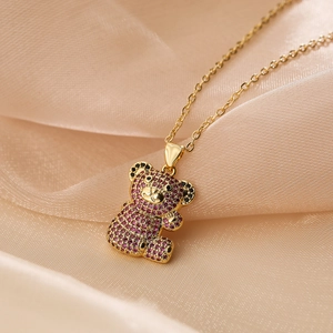 Macro shot of gold-plated bear pendant with purple and black zircon inlay detail