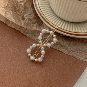 Detail of infinity-shaped gold hair clip adorned with dense white faux pearls on leather