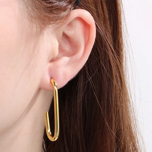 Gros plan d'un mannequin portant des boucles d'oreilles géométriques en U en acier doré