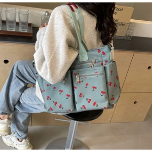 Detailed view of the light blue cherry print tote bag with multiple storage pockets