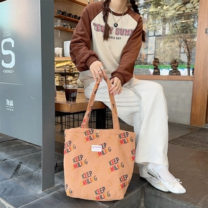 Detail view of orange corduroy tote bag with Keep Smiling print on a female model