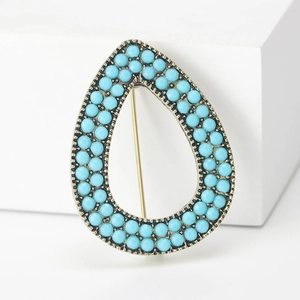 Bohemian teardrop brooch with turquoise beads on vintage gold metal base over white stand