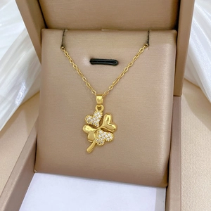 Detail of gold four-leaf clover necklace with sparkling cubic zirconia on brown gift box