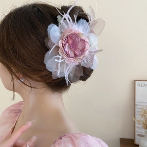 Detailed back view of a large 3D silk flower hair clip with feathers on a model hairstyle