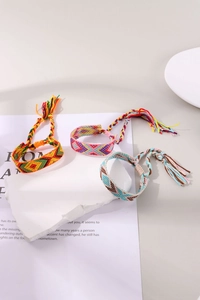 Detailed view of three colorful woven friendship bracelets with geometric patterns and tassels