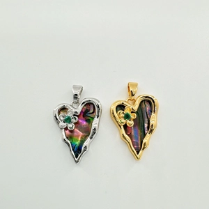 Gold and silver heart pendants with shell inlay and small flower details on white background