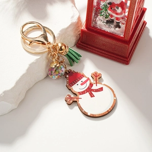 Charming wooden snowman keychain with green tassel and star-filled glass ball on rock pedestal