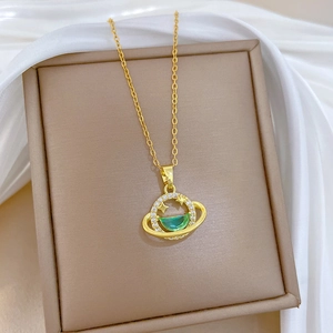 Elegant gold galaxy necklace with green zircon planet pendant on white silk background