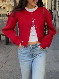 Detail of red knit cardigan with lantern sleeves and button closure on city street