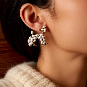 Close-up of vintage puppy stud earrings with pearls and crystals on a model's ear