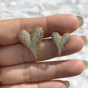 Luxurious gold heart stud earrings with shimmering clear crystals held in hand