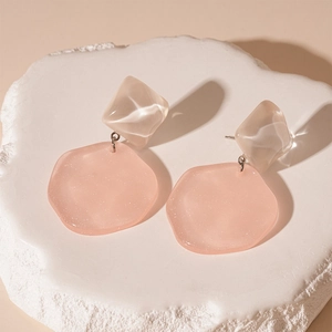 Detailed view of pink resin geometric earrings on a textured white stone display
