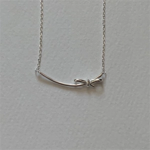 Macro detail of 925 sterling silver bow pendant with minimalist bar on delicate link chain