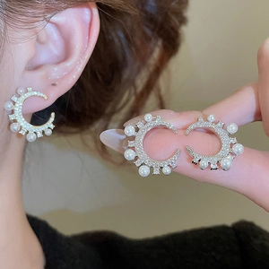 Detailansicht eleganter C-förmiger Ohrringe mit Zirkonia und Perlen direkt am Ohrläppchen