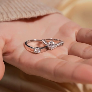 Matching crown couple rings with 1ct zircon stone and V-shaped band on silk background