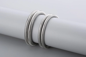 Détail de quatre bracelets serpent en acier inoxydable argenté sur un support rond