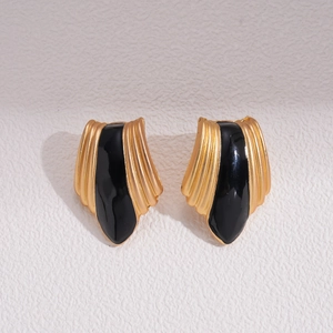 Detailed view of vintage gold earrings with black enamel inlay in a geometric shield shape