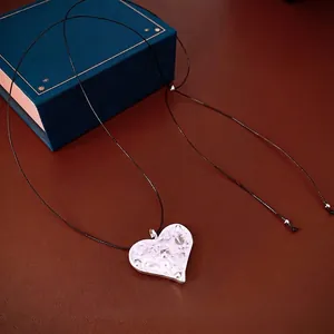 Minimalist silver heart pendant necklace with hammered texture on a black adjustable cord
