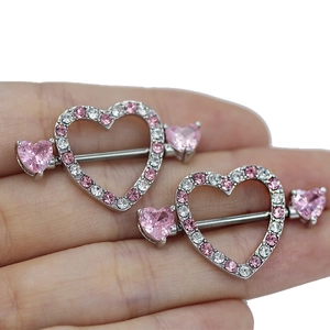 Close-up of pink heart nipple shield piercings with silver bar and shiny crystals