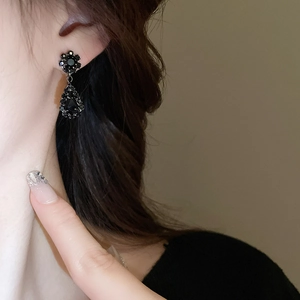 Close-up of elegant black waterdrop earrings with floral stud and crystal pendants
